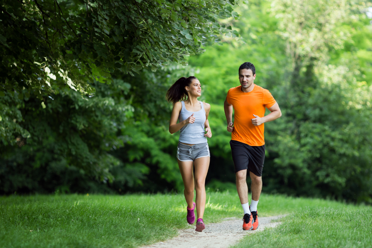 Couple jogging together outdoors on a tree-lined path after work