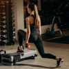 Woman performing a dumbbell strength training exercise in a well-equipped gym